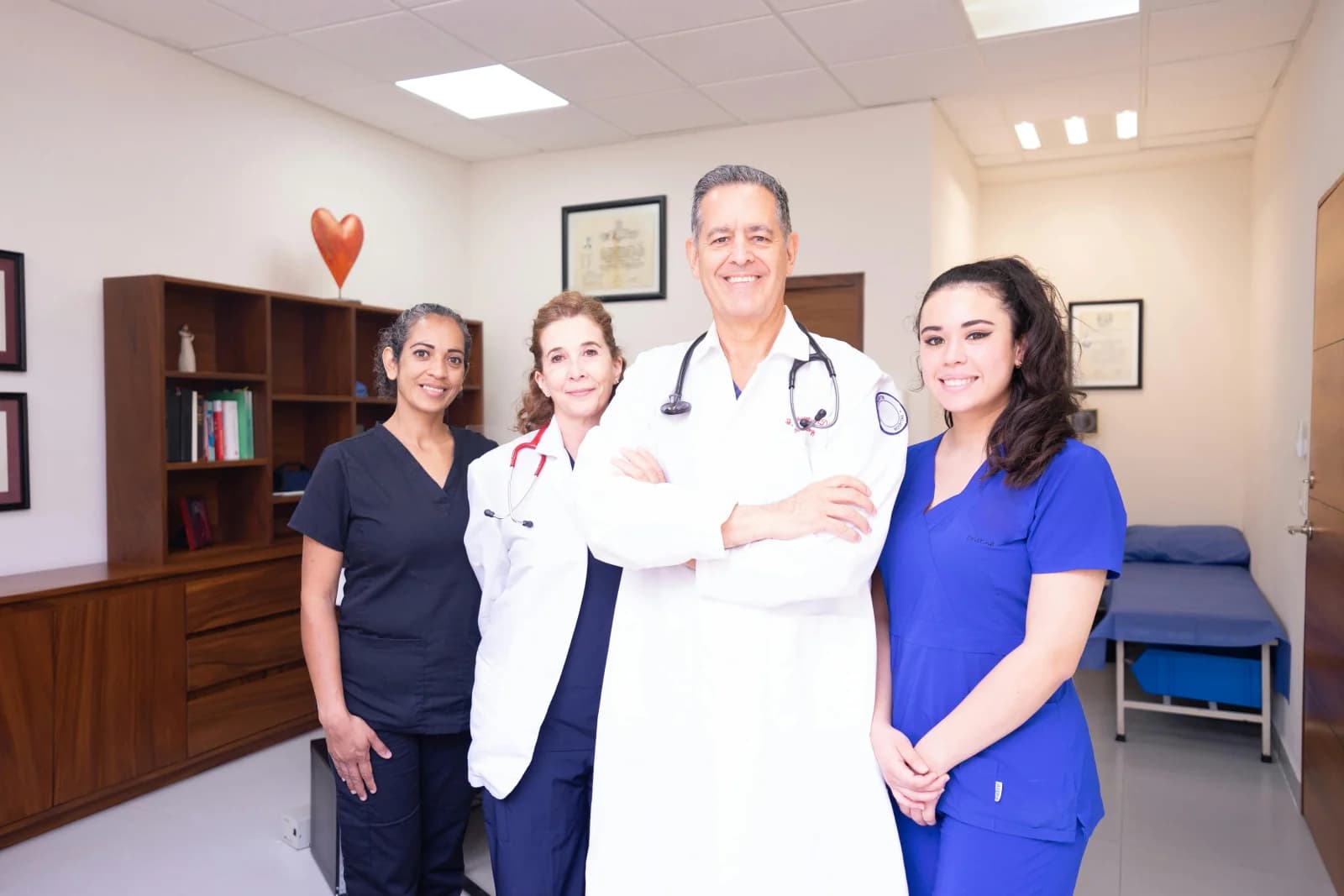 A clinical team — lead surgeon centred with three colleagues — standing in a modern consultation room